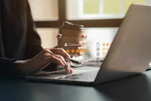 A person using a laptop and holding a coffee cup, with a digital overlay showing a five-star customer review rating on the screen—highlighting effortless review management.